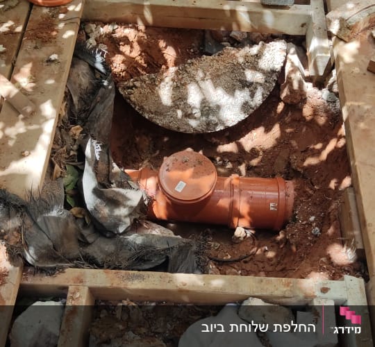 צינור כתום מונח בתוך חפירה באדמה